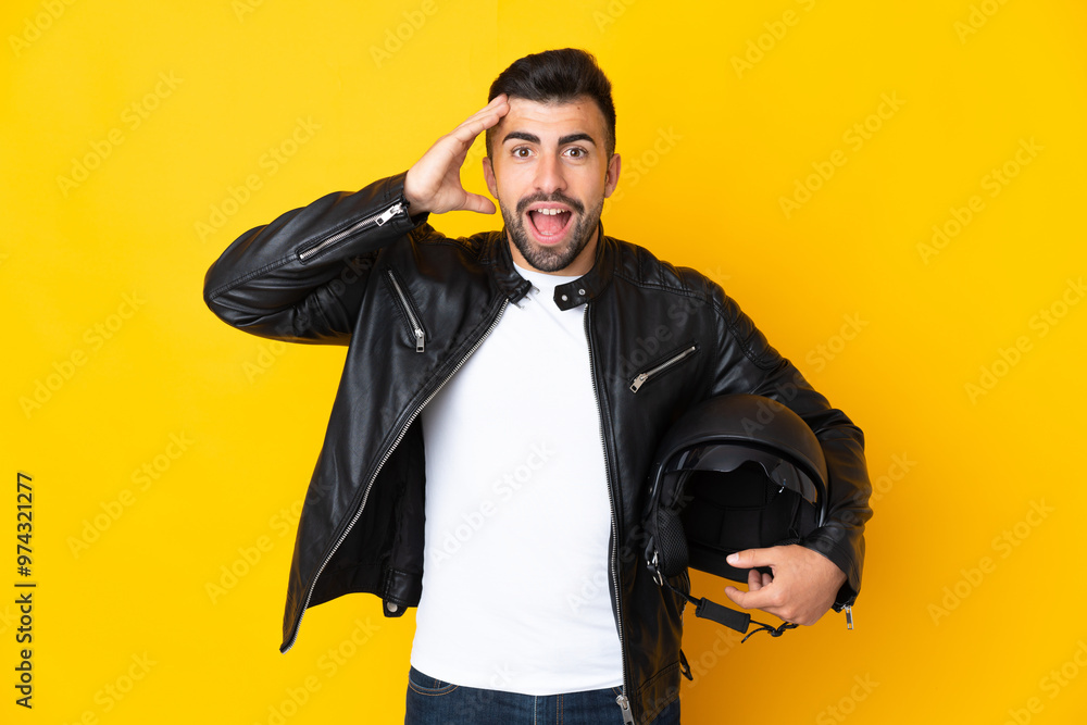 Caucasian man with a motorcycle helmet over isolated yellow background with surprise expression Caucasian man with a motorcycle helmet over isolated yellow background with surprise expression