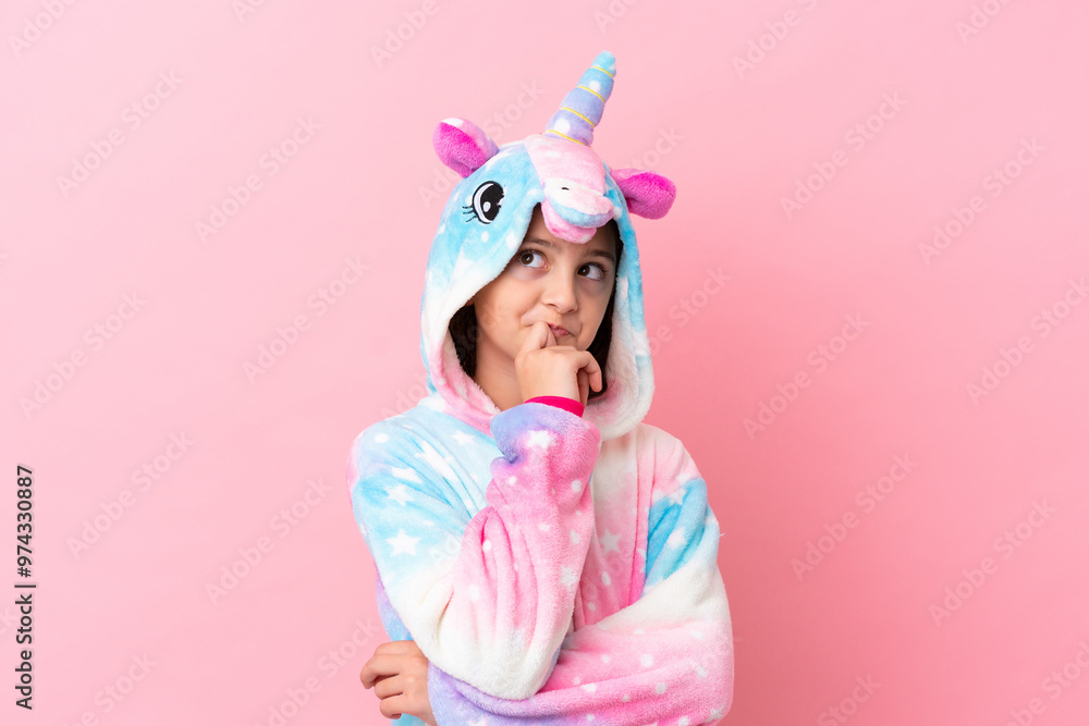 Little caucasian woman wearing a unicorn pajama isolated on pink background having doubts and thinking Little caucasian woman wearing a unicorn pajama isolated on pink background having doubts and thinking