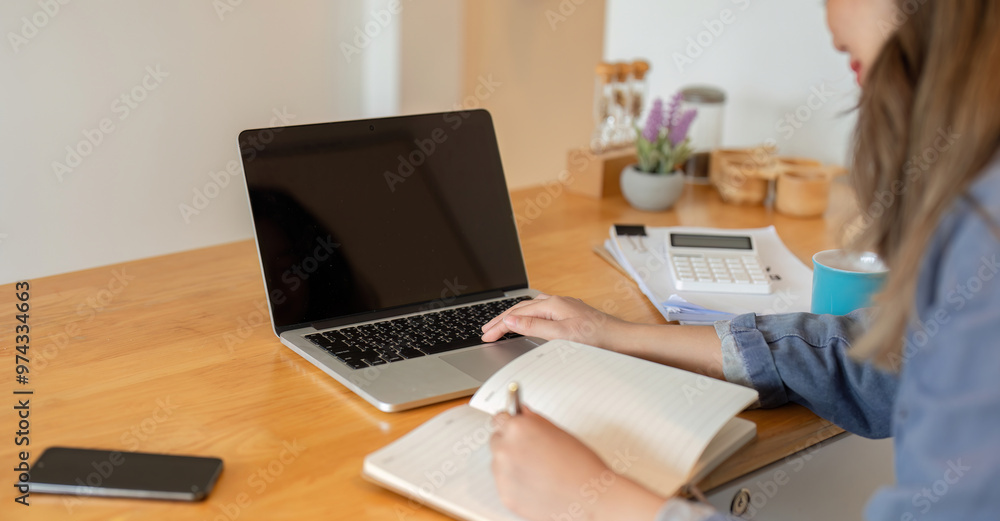 Female Freelancer Working from Home on Laptop and Taking Notes in a Modern Home Office Setting Female Freelancer Working from Home on Laptop and Taking Notes in a Modern Home Office Setting