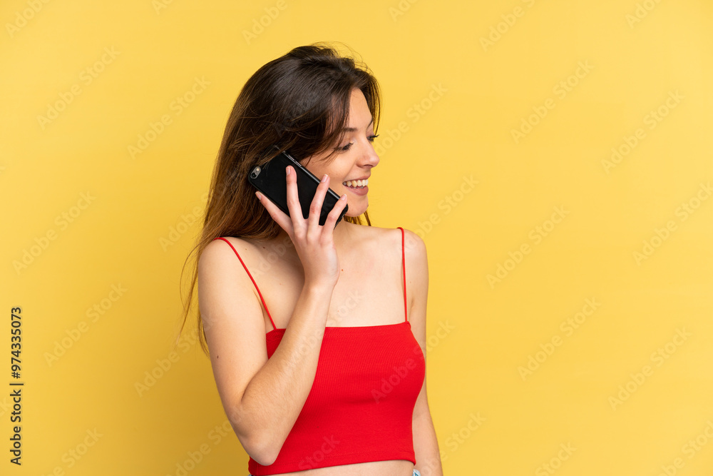 Young caucasian woman isolated on yellow background keeping a conversation with the mobile phone with someone Young caucasian woman isolated on yellow background keeping a conversation with the mobile phone with someone