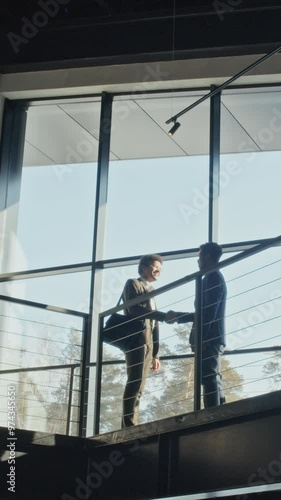 Wallpaper Mural Wide low-angle vertical shot of two young diverse businessmen in suits standing on passway by window in spacious lobby of hotel or office building, introducing each other, greeting with handshake Torontodigital.ca