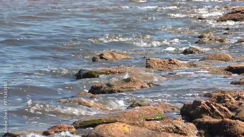 Windy weather, waves crashing on rocks and foaming in the salty hypersaline Kuyalnik estuary, Ukraine photo