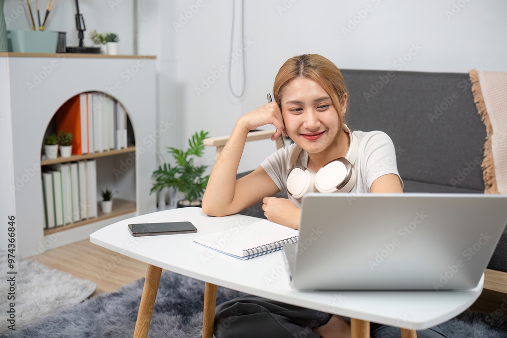 Young Woman Studying Online at Home with Laptop and Headphones in Modern Living Room Young Woman Studying Online at Home with Laptop and Headphones in Modern Living Room