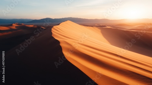 This photo captures a sunset over the large dunes in a vast desert, with dramatic shadows stretching across the sand, making a breathtaking and serene scenery.