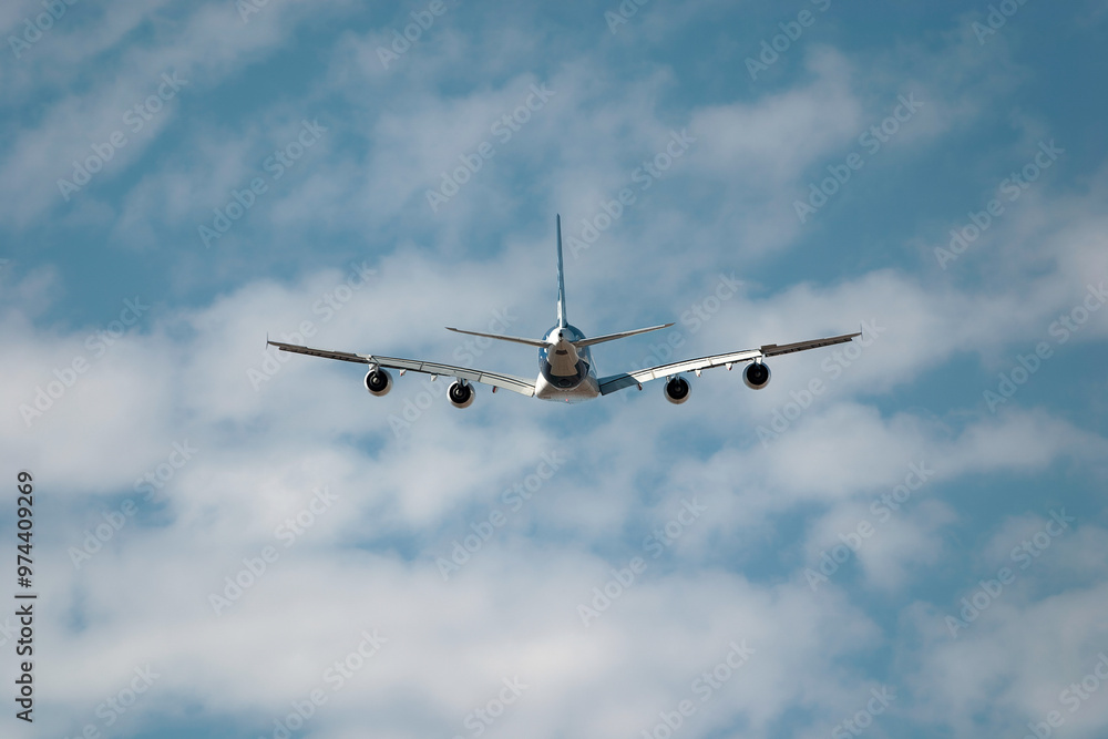 Passenger jet plane soars through a cloudy sky, symbolizing travel and freedom with a stunning backdrop of blue sky and white clouds Passenger jet plane soars through a cloudy sky, symbolizing travel and freedom with a stunning backdrop of blue sky and white clouds