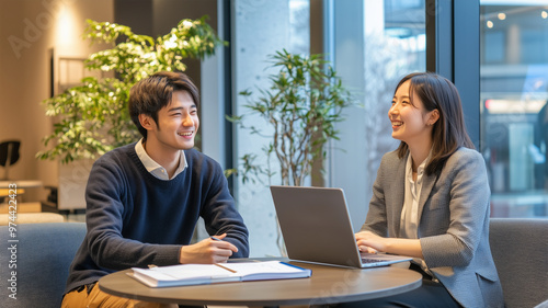 パソコンの前で笑顔で会話する日本人ビジネスマンとビジネスウーマン