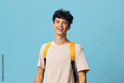 Photography cheerful young man with curly hair wearing a light t shirt and yellow backpack,