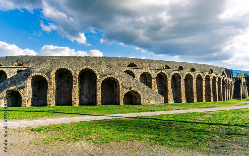 Obraz premium landscape of old ancient building of Roman arena with greeen grass foreground and beautiful blue cloudy sky background