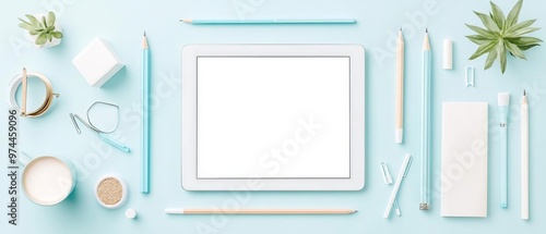 A flat lay of office supplies arranged around a tablet displaying a blank screen, ideal for promoting social media presence and digital identity photo