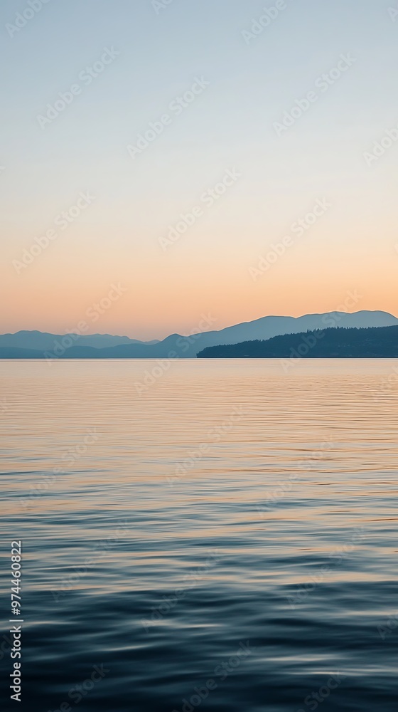 Fototapeta premium Tranquil Water Surface with Distant Mountain Range at Sunset.