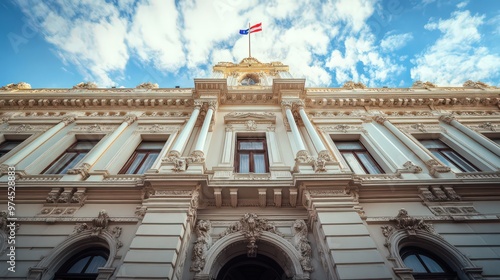 The facade of a historic government building with traditional architecture, ornate details, and a large flagpole displaying the national flag