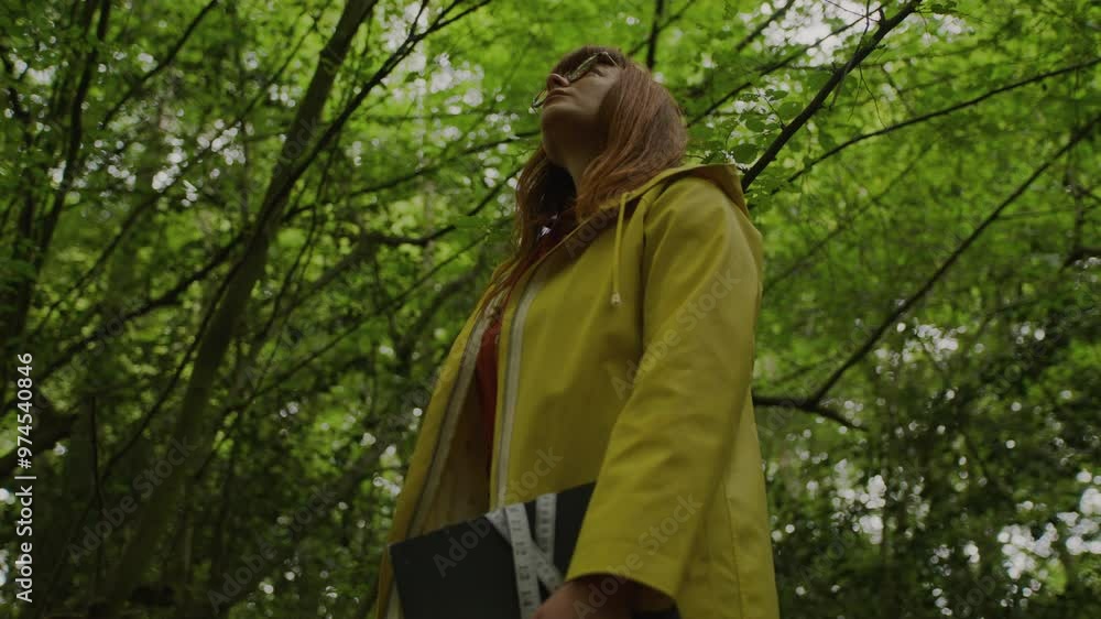 Ginger woman with yellow raincoat with glasses in forest Ginger woman with yellow raincoat with glasses in forest