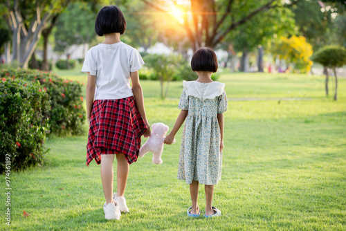 Two young girls are hugging each other in a park