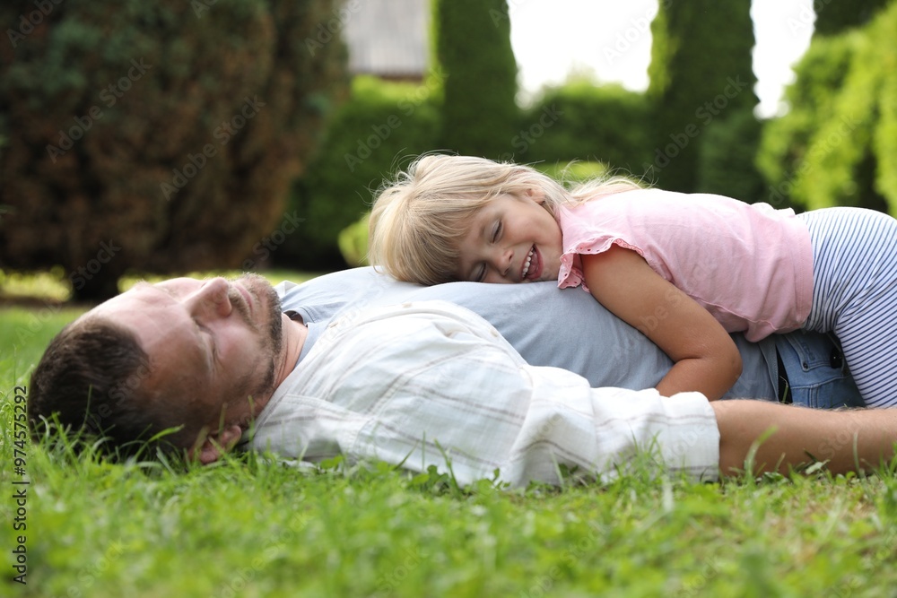 Father and his daughter spending time together on green lawn in park Father and his daughter spending time together on green lawn in park