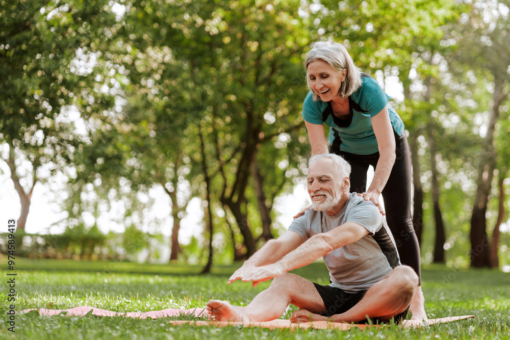 Fototapeta premium Senior couple is doing stretching exercises in the park, together training outdoors