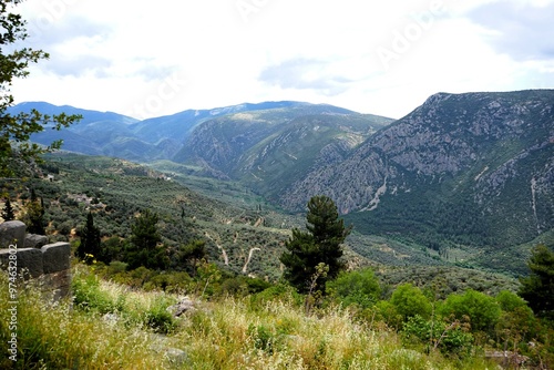 Ancient Greek ruins of the temple complex of the Oracle of Delphi in Greece with a breathtaking view of the panorama of the Pleistos River valley on a sunny summer's day  photo