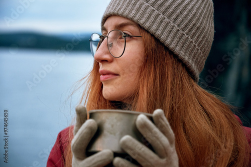 Canvas Print Pretty smiling female traveler drinking from thermos outdoors