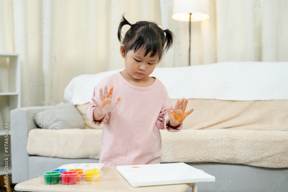 Asian toddler girl hands covered in orange paint, exploring the sensation and colors during finger painting. various paint colors, expressing creativity in indoor environment, learning art and play. Asian toddler girl hands covered in orange paint, exploring the sensation and colors during finger painting. various paint colors, expressing creativity in indoor environment, learning art and play.