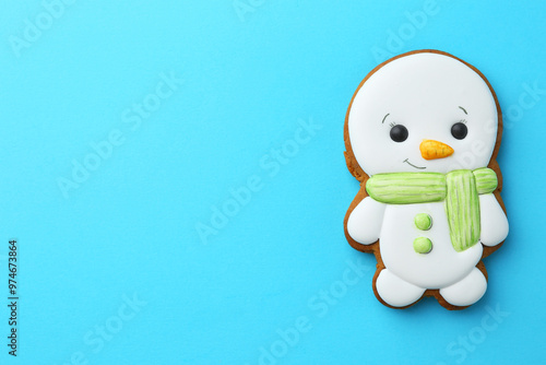 Tasty Christmas cookie in shape of snowman on light blue background, top view. Space for text