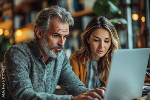 A man and a woman look intently at a laptop screen.