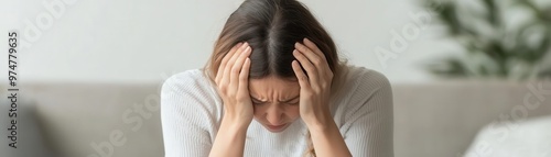 Woman with head in her hands, sitting on a couch, representing the emotional impact of infertility infertility, emotional struggle