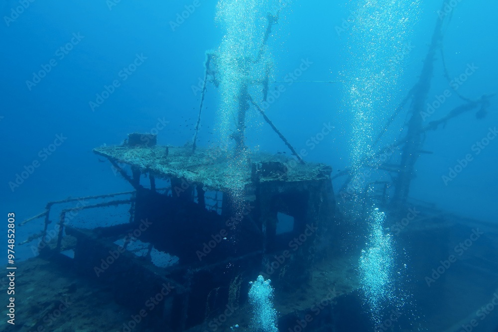 Bubbles from scuba diving on the boat wreckage. Travel photo, seascape and wreck. Deep blue ocean with the rusty metal shipwreck. Scuba diving trip, adventure deep wreck exploration. Bubbles from scuba diving on the boat wreckage. Travel photo, seascape and wreck. Deep blue ocean with the rusty metal shipwreck. Scuba diving trip, adventure deep wreck exploration.