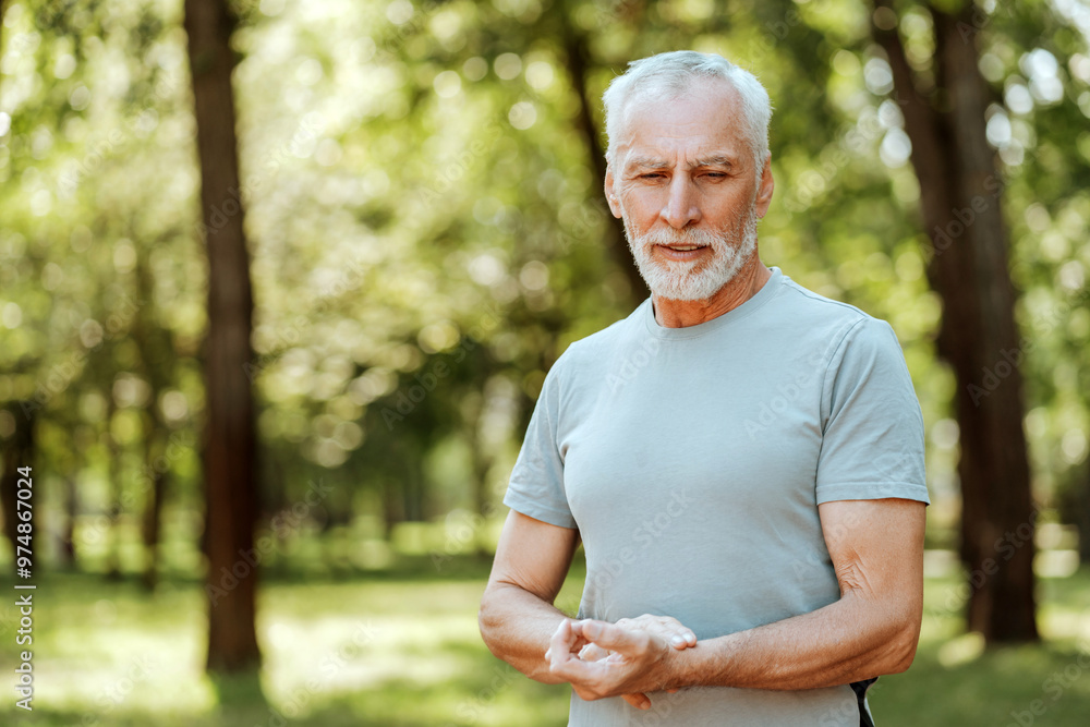 Senior man taking a break and checking pulse while exercising outdoors Senior man taking a break and checking pulse while exercising outdoors