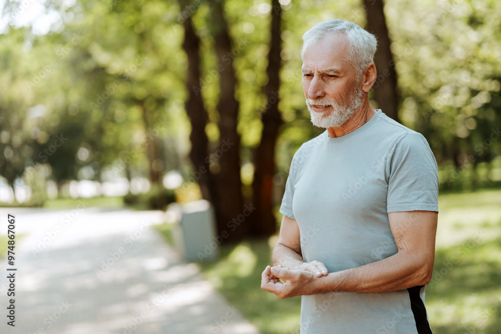 Serious senior man taking a break and checking pulse while exercising outdoors, copy space Serious senior man taking a break and checking pulse while exercising outdoors, copy space