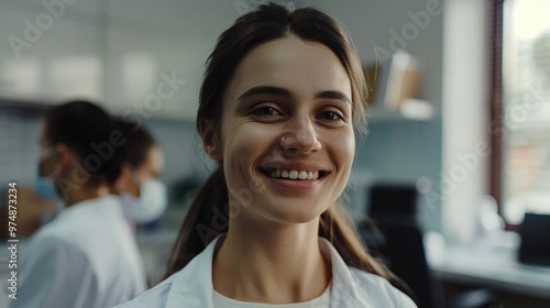 A smiling woman wearing a lab coat poses for the camera