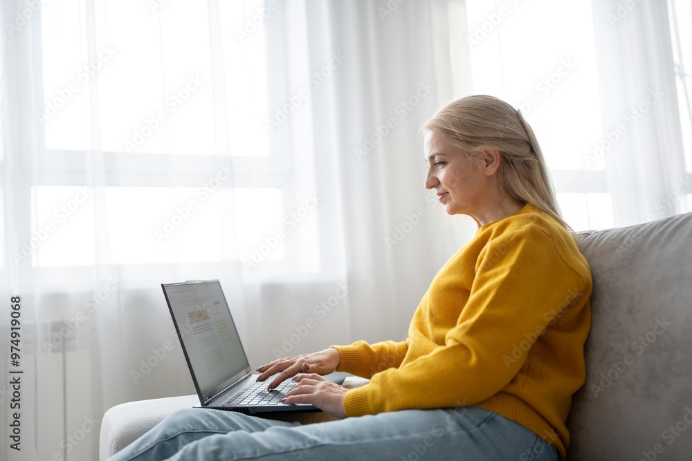 Naklejka premium Blonde woman in sweater types on laptop in welllit living room, creating productive workspace