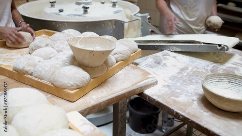 Workers shaping dough using a round dough molder in a bakery