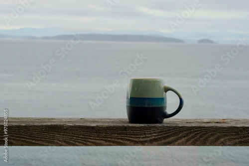 Coffee mug on a wooden rail looking out to the ocean