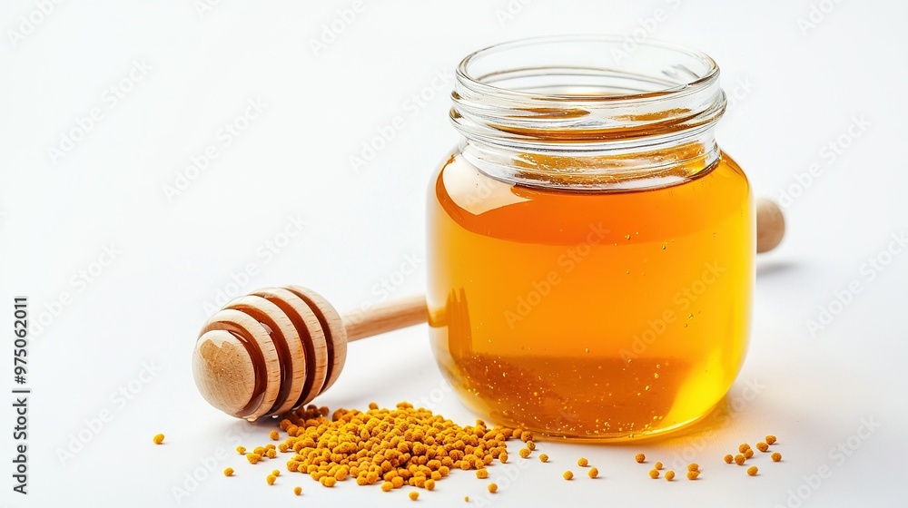 A jar of honey next to a wooden honey dipper on a white background A jar of honey next to a wooden honey dipper on a white background