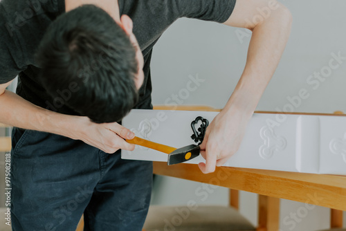 A young man repairs a retro handle on a drawer.