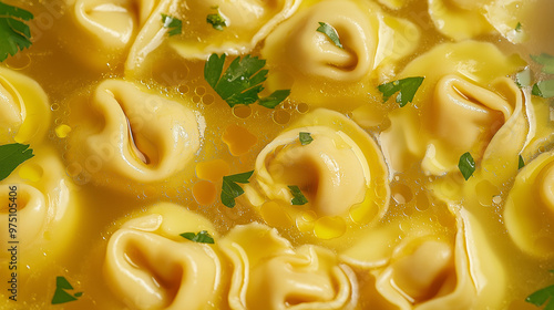 a close-up, top-down view of tortellini in brodo, filling the entire frame with the focus on the pasta's intricate details