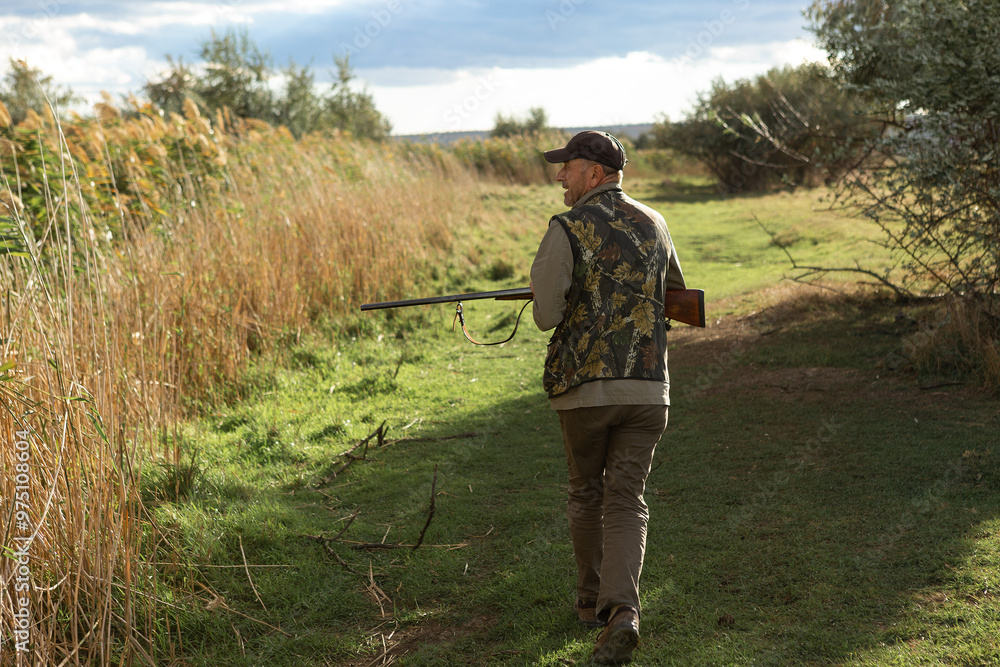 Mature man hunter with gun while walking on field. Mature man hunter with gun while walking on field.