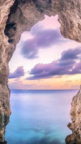 A photograph of a natural cave with calm, serene water. A view from inside a cave looking out, with a stunning sunset sky.