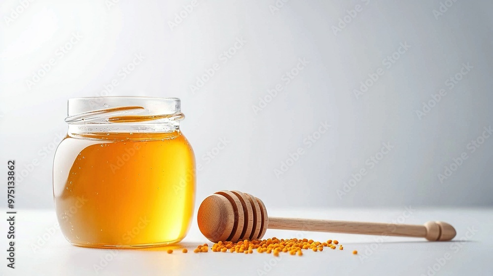 A jar of honey sits beside a wooden spoon, with a honey dipper nearby on a white background A jar of honey sits beside a wooden spoon, with a honey dipper nearby on a white background