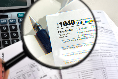 Tax accounting in united states. Form 1040 US income tax return. Concept of tax filing services in America. Report on government payments under magnifying glass. Pen and calculator near form 1040 photo