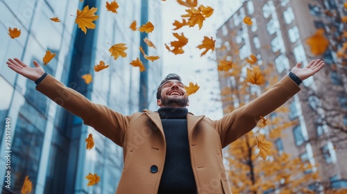 Joyful businessman celebrates success by tossing yellow maple leaves in city park with skyline view photo