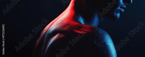 A dramatic close-up of a man's shoulder with artistic lighting highlighting the muscular contours in vibrant colors.
