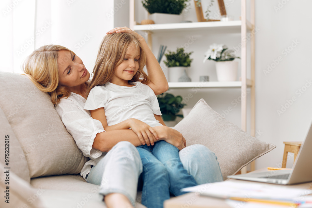 Mother and daughter bonding moment on the couch, working together on a laptop for online activities and learning Mother and daughter bonding moment on the couch, working together on a laptop for online activities and learning