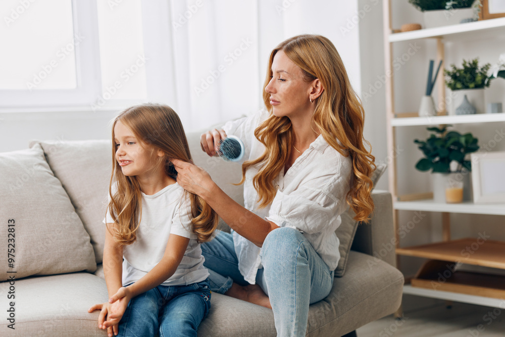 Mother and daughter bonding time as mom carefully combs her child's hair on a cozy living room couch Mother and daughter bonding time as mom carefully combs her child's hair on a cozy living room couch