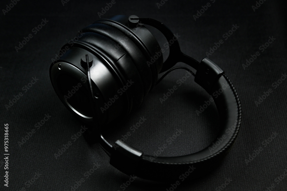 A sleek black headphone with cushioned ear cups, adjustable headband, and high-quality sound, set against a black background. A sleek black headphone with cushioned ear cups, adjustable headband, and high-quality sound, set against a black background.