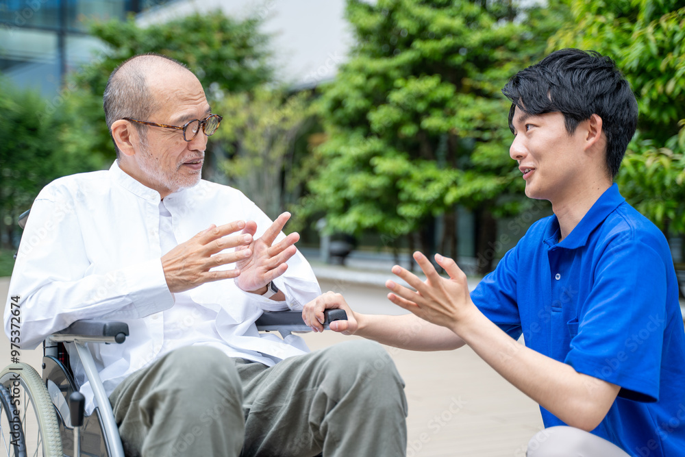 Obraz premium 車いすのシニア男性と介護施設スタッフ