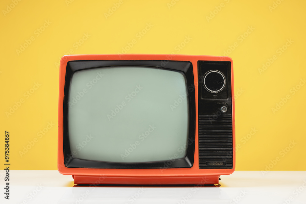 Old retro red TV on white table with blank screen on yellow background, front view. Old retro red TV on white table with blank screen on yellow background, front view.