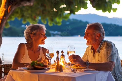 Senior couple sitting at table on terrace with sea view at sunset