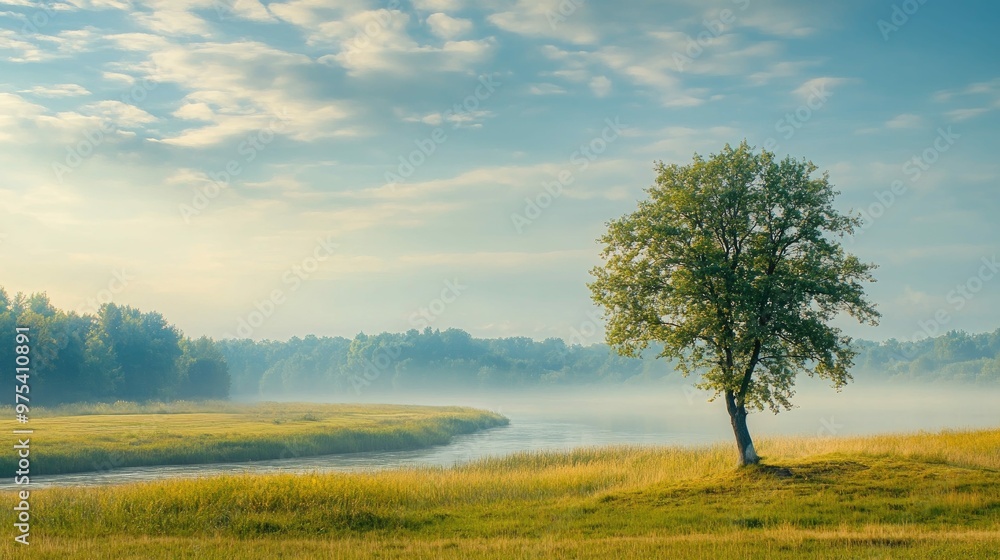 A lone tree stands on the edge of a river, with a hazy forest in the background and a blue sky with white clouds overhead. A lone tree stands on the edge of a river, with a hazy forest in the background and a blue sky with white clouds overhead.