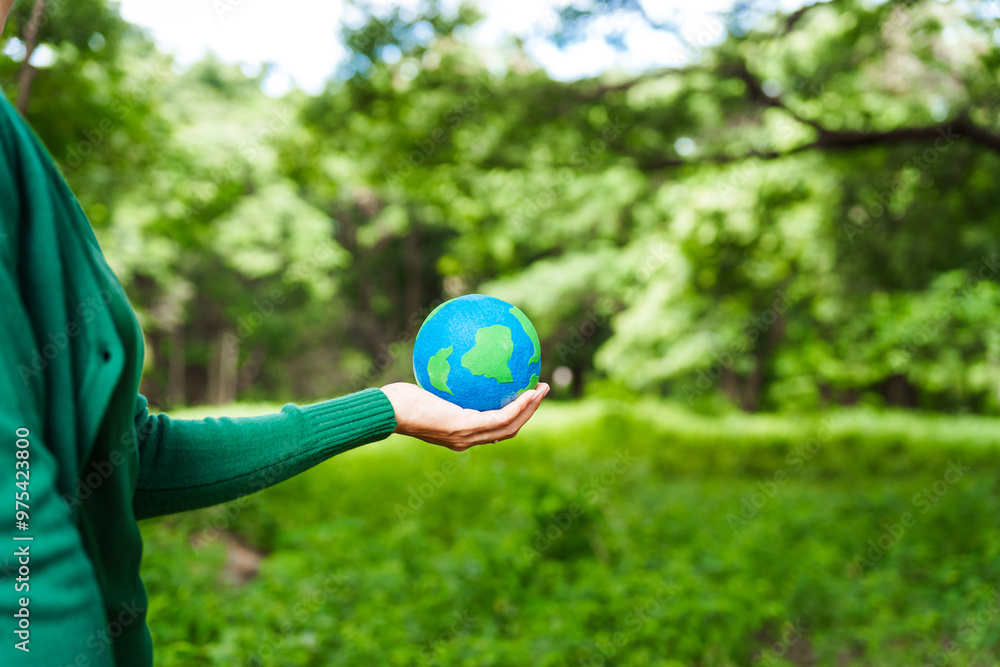 Forest conservationist holds small globe in hands, symbolizing global responsibility for protecting planet. Standing outdoors in green park, sustainability, commitment to achieving net-zero impact. Forest conservationist holds small globe in hands, symbolizing global responsibility for protecting planet. Standing outdoors in green park, sustainability, commitment to achieving net-zero impact.
