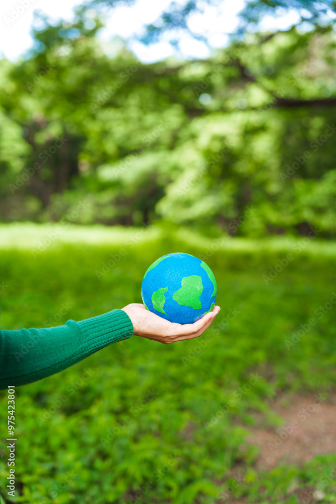 Forest conservationist holds small globe in hands, symbolizing global responsibility for protecting planet. Standing outdoors in green park, sustainability, commitment to achieving net-zero impact. Forest conservationist holds small globe in hands, symbolizing global responsibility for protecting planet. Standing outdoors in green park, sustainability, commitment to achieving net-zero impact.